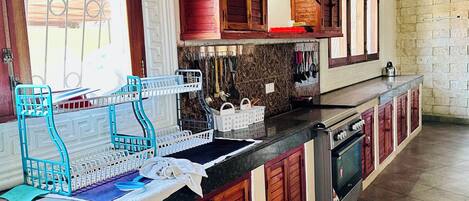 Una cucina con mobili in legno, forno a incasso e una finestra con inferriate decorative.
