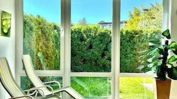 Una habitación con un ventanal grande, dos sillones de descanso y una planta en maceta.