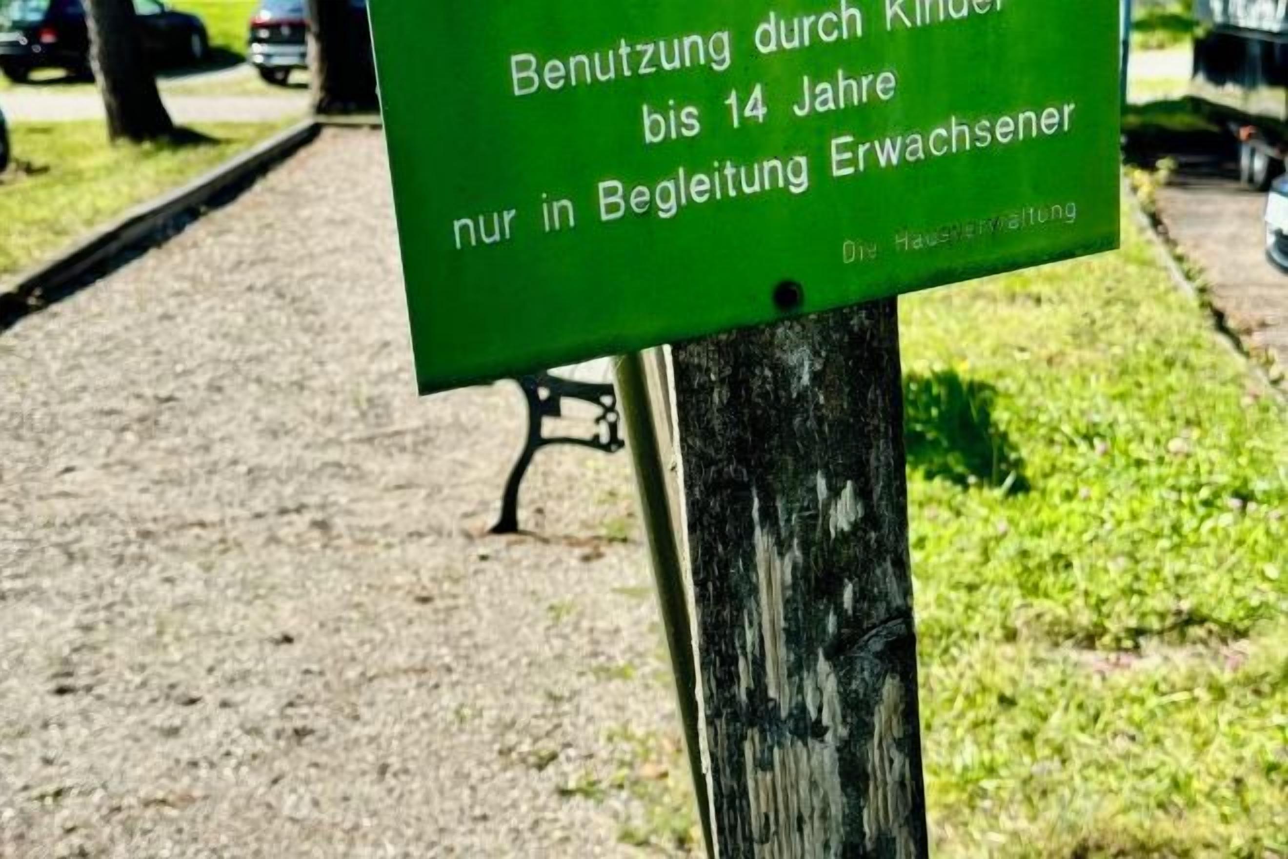 Uma placa verde com texto branco numa estaca de madeira.