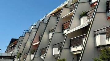 Edifício residencial com várias andares e varandas, algumas com plantas.