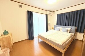 A bedroom with a wooden bed, a small bedside table, a trash bin, and a window with curtains. - 4 bedrooms, 2 bathrooms, 2 toilets, spacious house with convenient transportation (Kyoto)