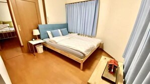 A bedroom with a bed, a nightstand, a lamp, and a small table with a book. - 4 bedrooms, 2 bathrooms, 2 toilets, spacious house with convenient transportation (Kyoto)