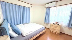 Une chambre à coucher avec un lit, une commode et une fenêtre avec des rideaux.