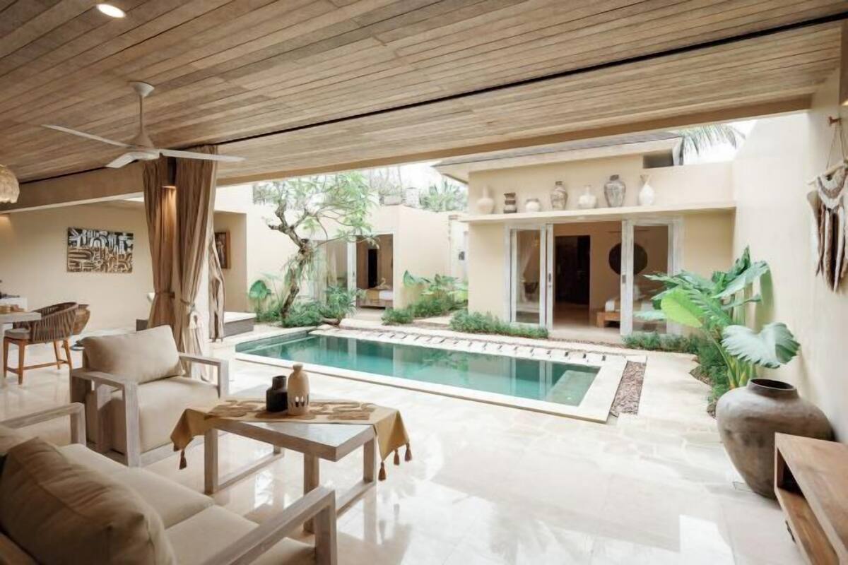 A modern outdoor living area with a pool, seating, and a ceiling fan.