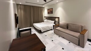 Et moderne hotelværelse med seng, sofa, skrivebord og loftventilator.