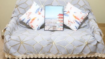 A sofa with a geometric pattern and a cushion with a landscape print.