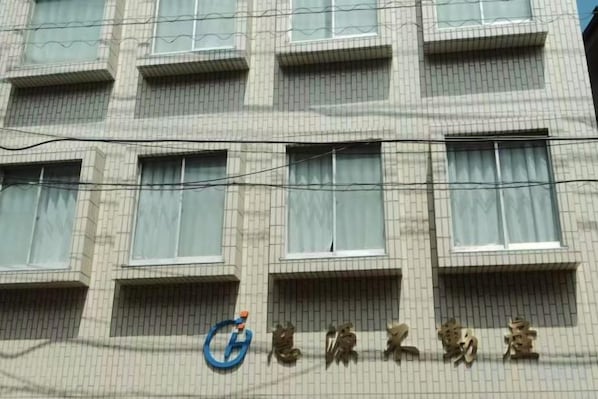 A multi-story building with a series of windows and a logo on the facade.