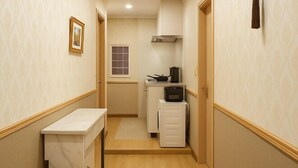 A narrow hallway with a kitchenette area, including a stove, microwave, and cabinets. - sakuranoyado2 (Tokyo)