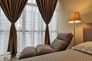 Un dormitorio moderno con un ventanal grande, una lámpara de pie y un sofá.
