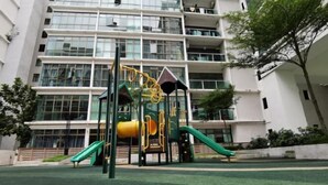 A playground with slides and climbing structures in front of a multi-story building. - Palazio Studio Mount Austin Toppen Ikea by JYNest Johor (Johor Bahru)