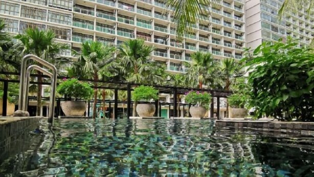 A hotel with a large indoor pool surrounded by lush greenery and palm trees. - Palazio Studio Mount Austin Toppen Ikea by JYNest Johor (Johor Bahru)