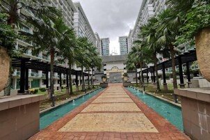 A pool area with a central walkway, surrounded by high-rise buildings and palm trees.