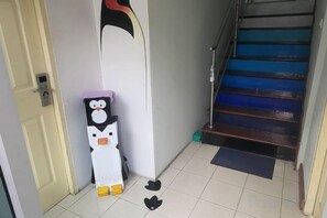 Una esquina con una puerta blanca, una figura de pingüino blanco y negro, y una escalera azul.