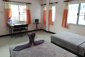 A hotel room with two beds, a desk with a chair, a small table, and curtains. - Ocean Room (Bangkok)