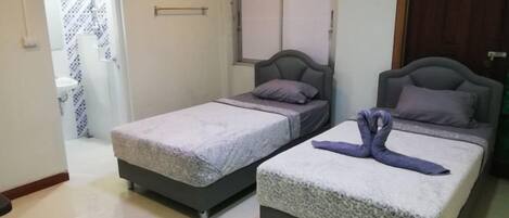 A room with two beds, a door, a window, and a wardrobe.