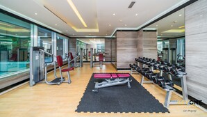 Een moderne sportschool met trainingsapparatuur, een spiegelwand en een houten vloer.