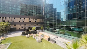 Een modern gebouw met een glazen gevel, een dakterras met zitplaatsen en een zwembad.