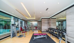 A modern gym with exercise equipment, a mirrored wall, and a wooden floor.