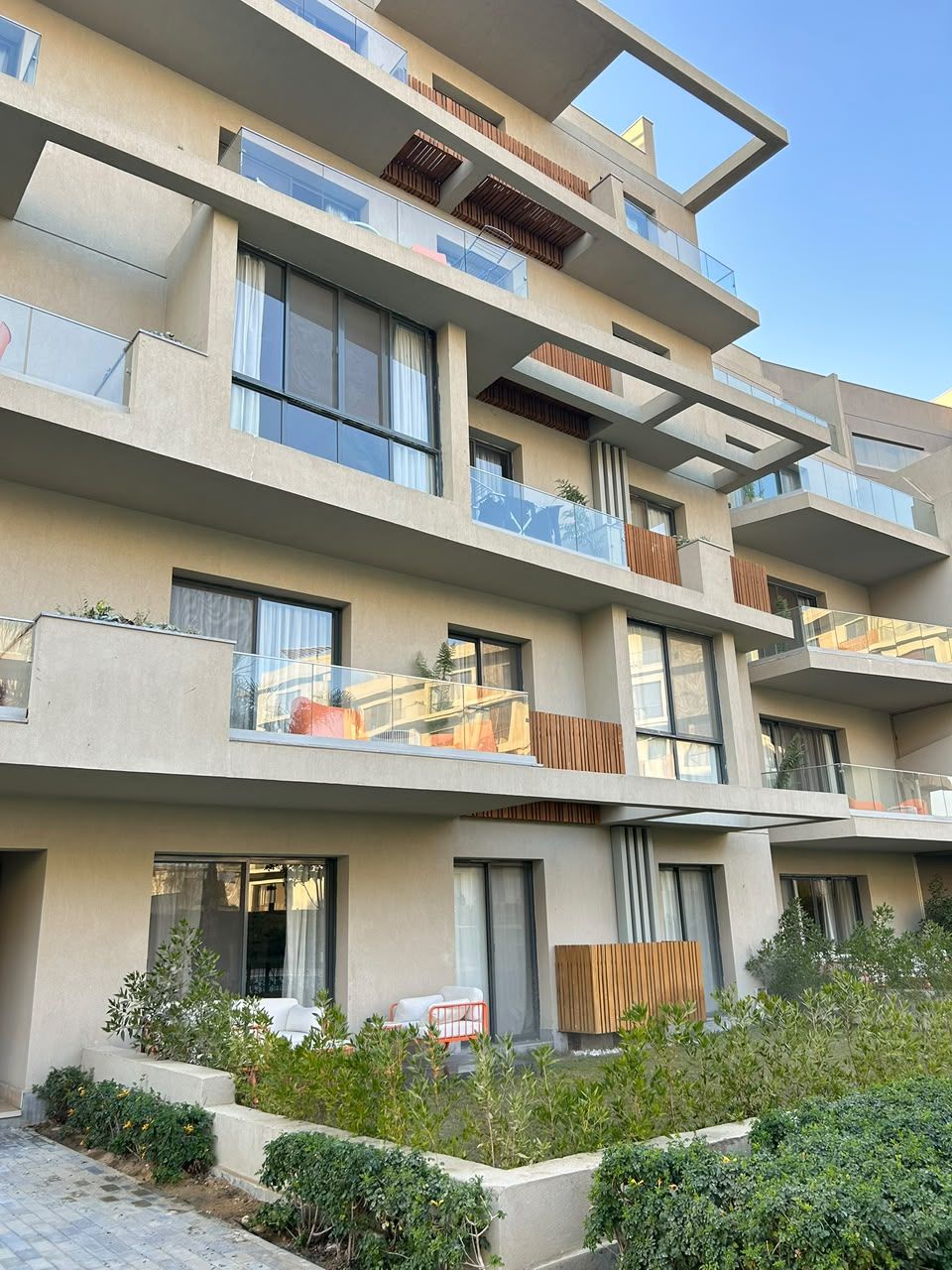 Un edificio a più piani con balconi, ampie finestre e un giardino curato.