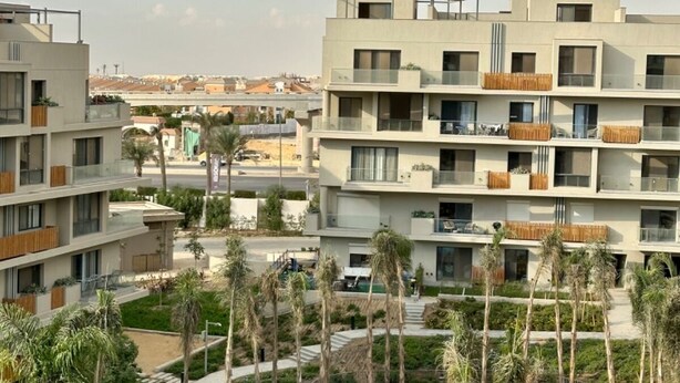 Een modern hotel met meerdere verdiepingen, een zwembad en palmbomen.
