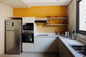 Een koelkast, een microgolfoven, een oven, kookgerei, borden en bestek