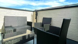 An outdoor seating area with wicker furniture and a view of the sky. - Yahiro 6chome (Tokyo)