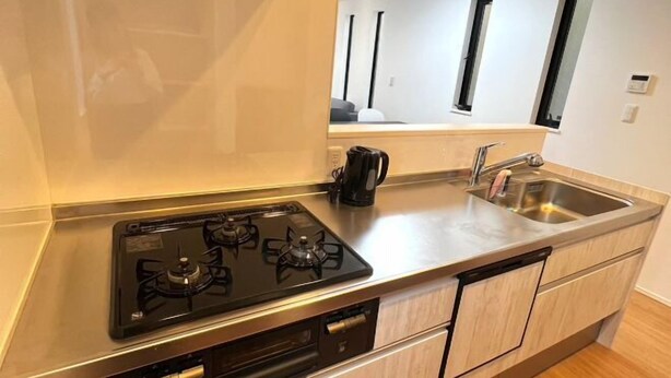 A modern kitchen with a gas stove, a coffee maker, and a sink. - Yahiro 6chome (Tokyo)