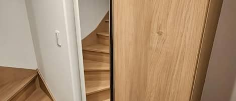 A wooden staircase leading to a room with white walls and a door.