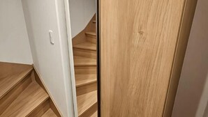 A wooden staircase leading to a room with white walls and a door. - Yahiro 6chome (Tokyo)