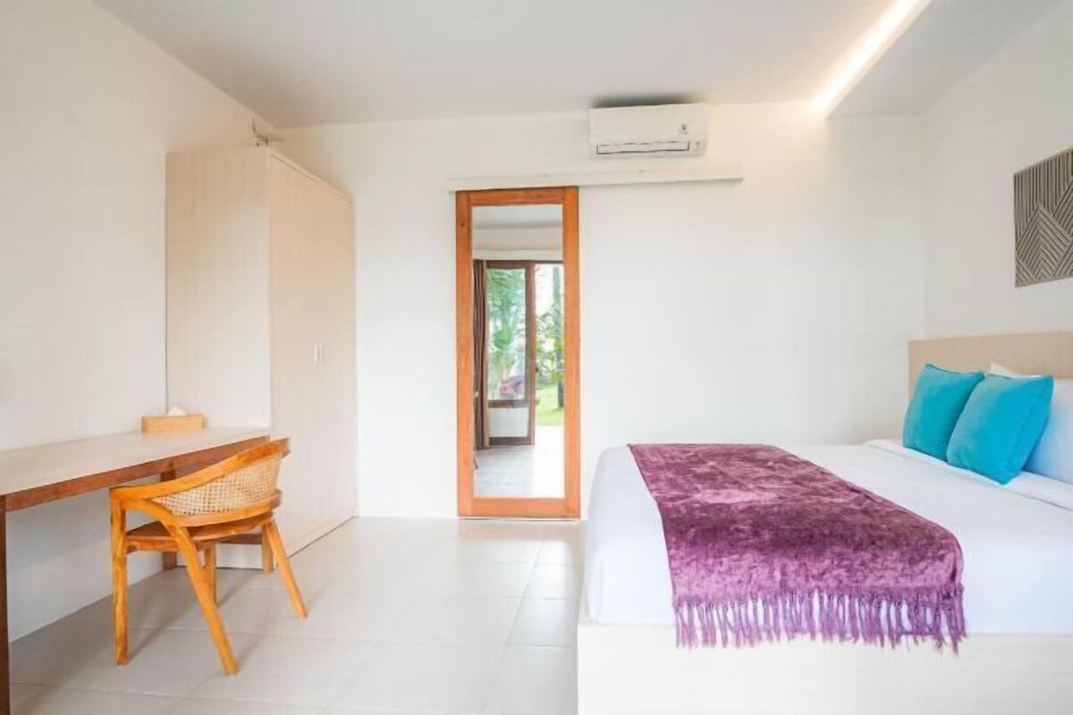 Une chambre à coucher avec un lit, un bureau, une chaise et une vue sur l’extérieur.