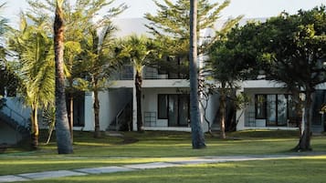 Una casa moderna con techo plano, amplios ventanales y un césped cuidado con palmeras.