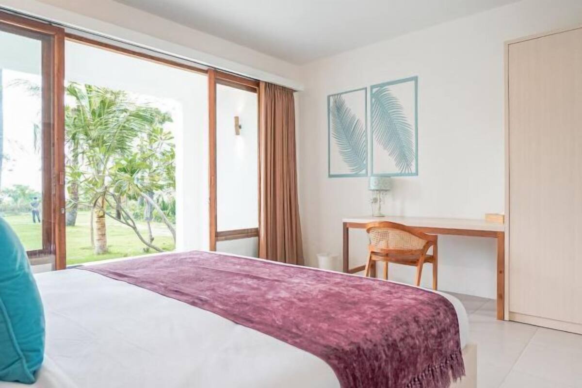 Une chambre d’hôtel équipée d’un lit, d’un bureau, d’une chaise et offrant une vue sur l’extérieur.