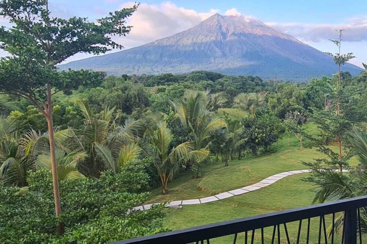 Un balcon donnant sur un jardin luxuriant et une montagne.