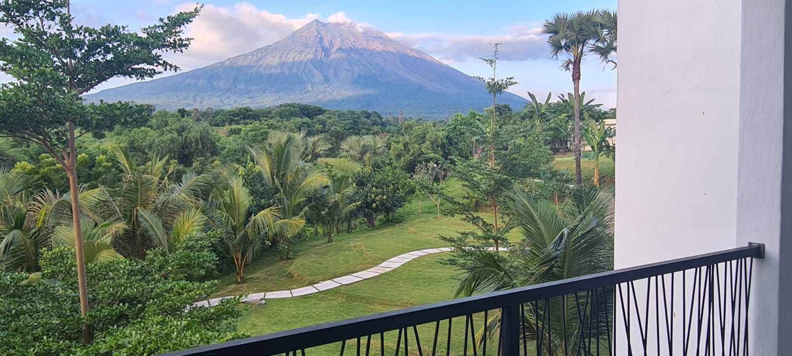 Un balcón con vistas a un jardín exuberante y una montaña.