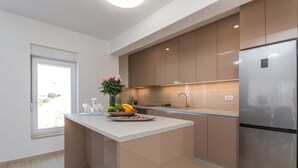 Una cocina moderna con una isla central, electrodomésticos de acero inoxidable y vistas al exterior.