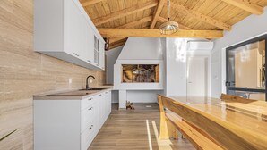 Una cocina moderna con armarios blancos, encimera de madera y techo de madera.