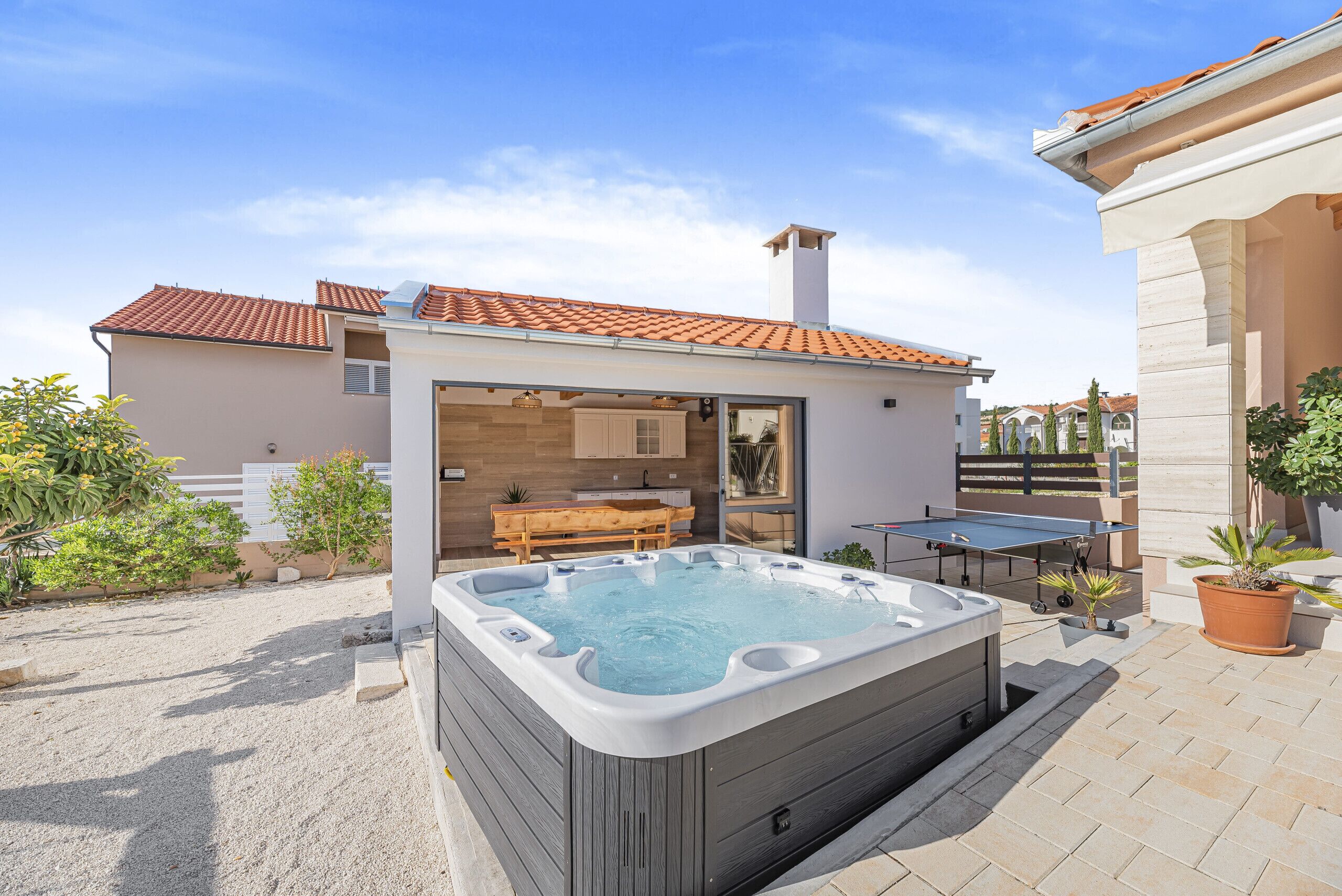 A modern house with a hot tub, outdoor seating, and a dining area.