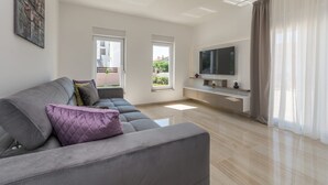 Una sala de estar moderna con un sofá gris, un televisor de pantalla plana y un diseño minimalista.