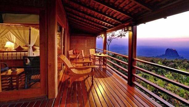 Une terrasse en bois offrant une vue sur l’océan et un bâtiment doté d’un porche abrité.