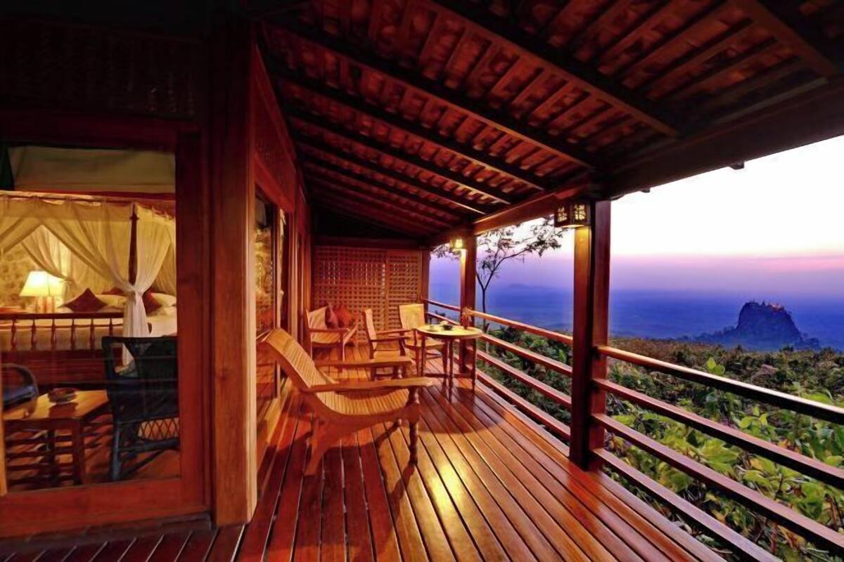 A wooden deck with a view of the ocean and a building with a covered porch.
