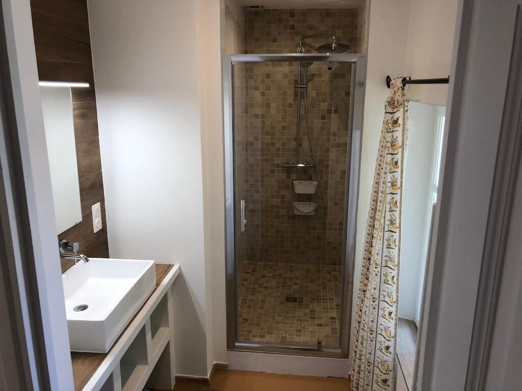 A bathroom with a glass-enclosed shower, a white sink, and a mirror.