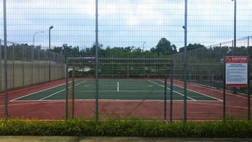 A fenced tennis court with a caution sign.