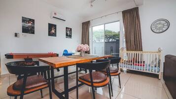 Uma sala de jantar com mesa e cadeiras de madeira, um berço e vista para o exterior.