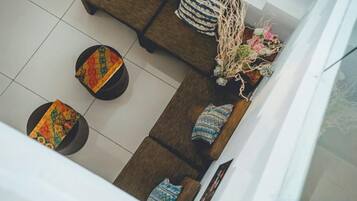 A high-angle view of a modern living area with a sofa, two ottomans, and a decorative vase.