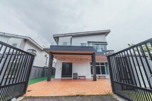 A modern two-story house with a covered entrance, a gated driveway, and a visible staircase leading to the entrance.