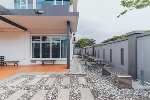 A building with a covered patio area, outdoor seating, and a gravel pathway.