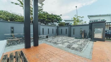 A courtyard with a tiled floor, a wooden bench, and a metal gate.