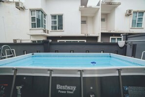 A rectangular swimming pool with a ladder on one side, surrounded by a black and white pool enclosure.