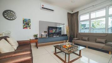 Uma sala de estar moderna com sofá, mesa de centro, televisão e janela com cortinas.