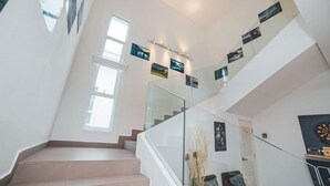 A modern staircase with glass railings and artwork on the walls. - d'Lux 6BR16-25px Pool/BBQ/NetFlx/HotPot/KTV/Mahjong (Bandar Penawar)
